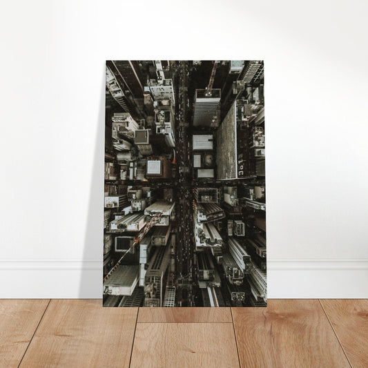 Vertical aerial view of a city skyline with tall buildings and intersecting streets in monochrome tones.