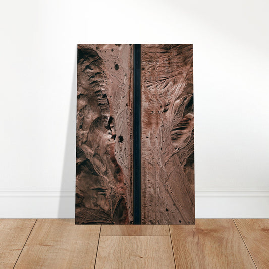 A solitary road cuts through rugged desert terrain, surrounded by earthy textures and expansive wilderness.