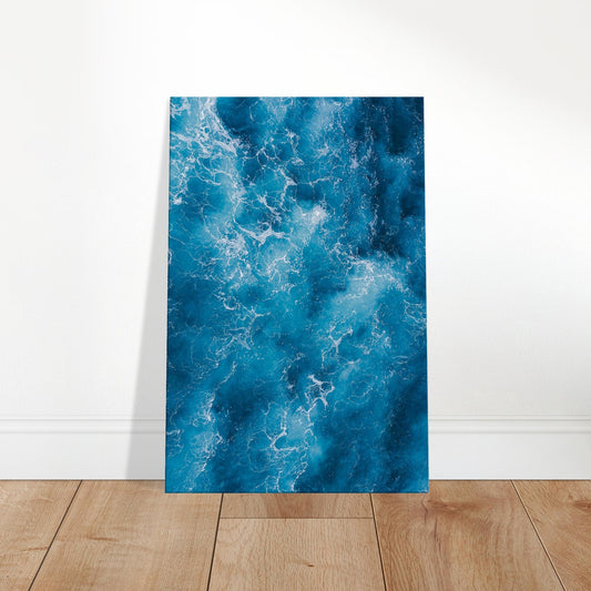 Aerial view of ocean waves swirling in deep blue and white foam, resembling abstract movement on the sea surface.
