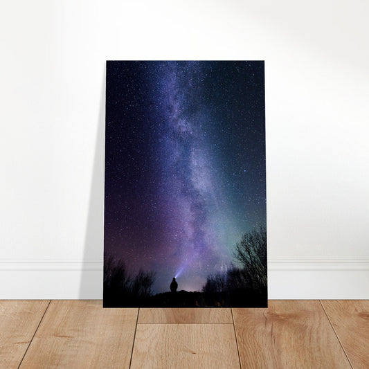 Milky Way galaxy over a silhouetted figure with a beam of light under a vast star-filled night sky.